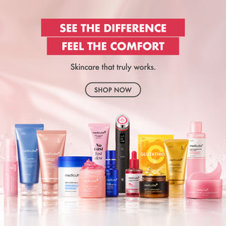 A promotional skincare lineup from Medicube displayed on a glossy white surface against a soft pink background. The products include various tubes, jars, and bottles in pink, blue, gold, and white packaging.